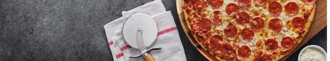 Pizza auf einem Holzbrett mit einem Pizzaschneider