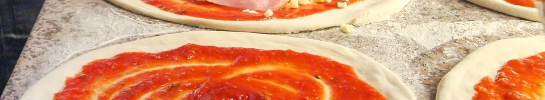 Pizzatisch mit Pizzateig und Tomatensoße