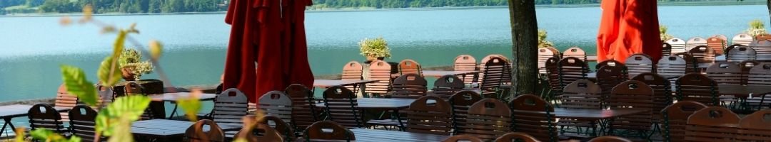 Biergarten am Wasser mit Tische, Stühle und Sonnenschirme